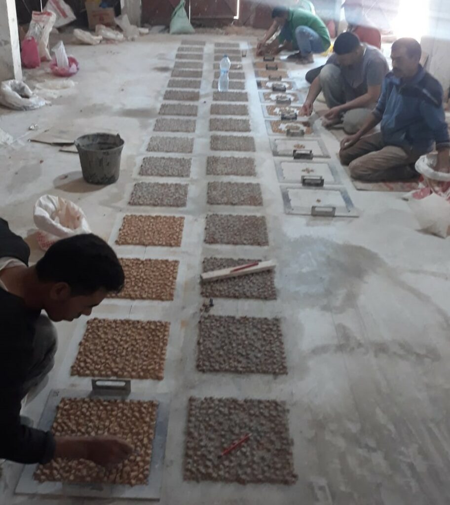 des artisans travaillant par terre pour rassembler des zellige sur filet